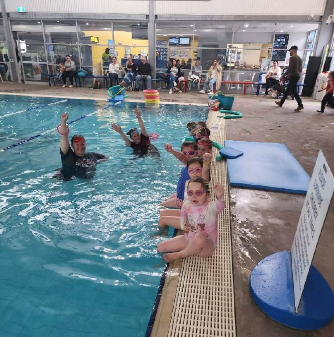 Young swimmers raised their fists in the air, which is a signal for help in the water. Picture supplied. 