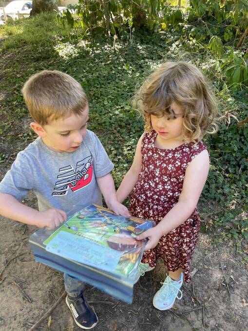 Four-year-old twins Christopher and Isabelle found this stack of hidden books at Seymour Park in Moss Vale. Photo supplied.